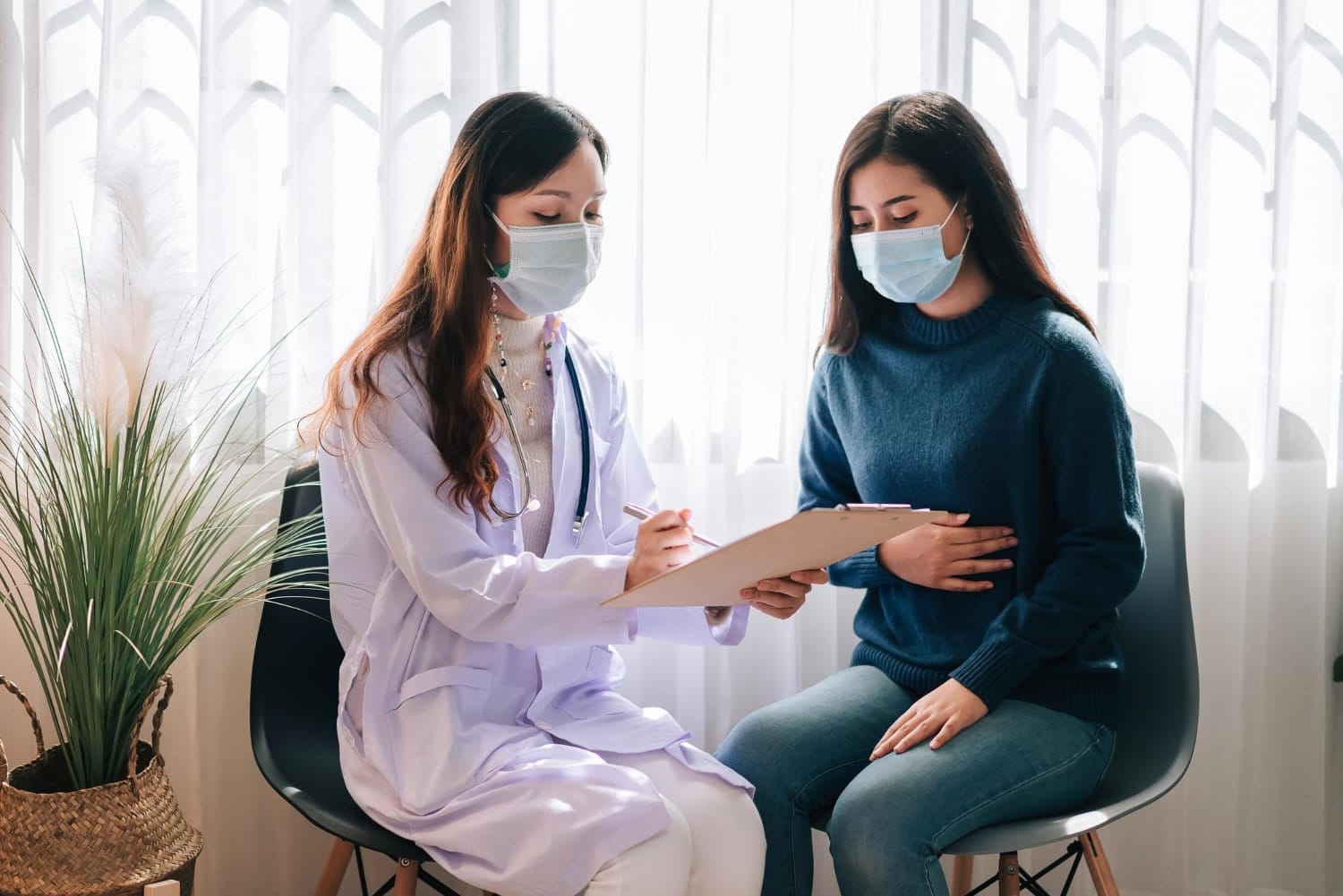 Urine Drug Test: Purpose, What to Expect, and Results 1 asian female doctor examines young adult both wearing masks