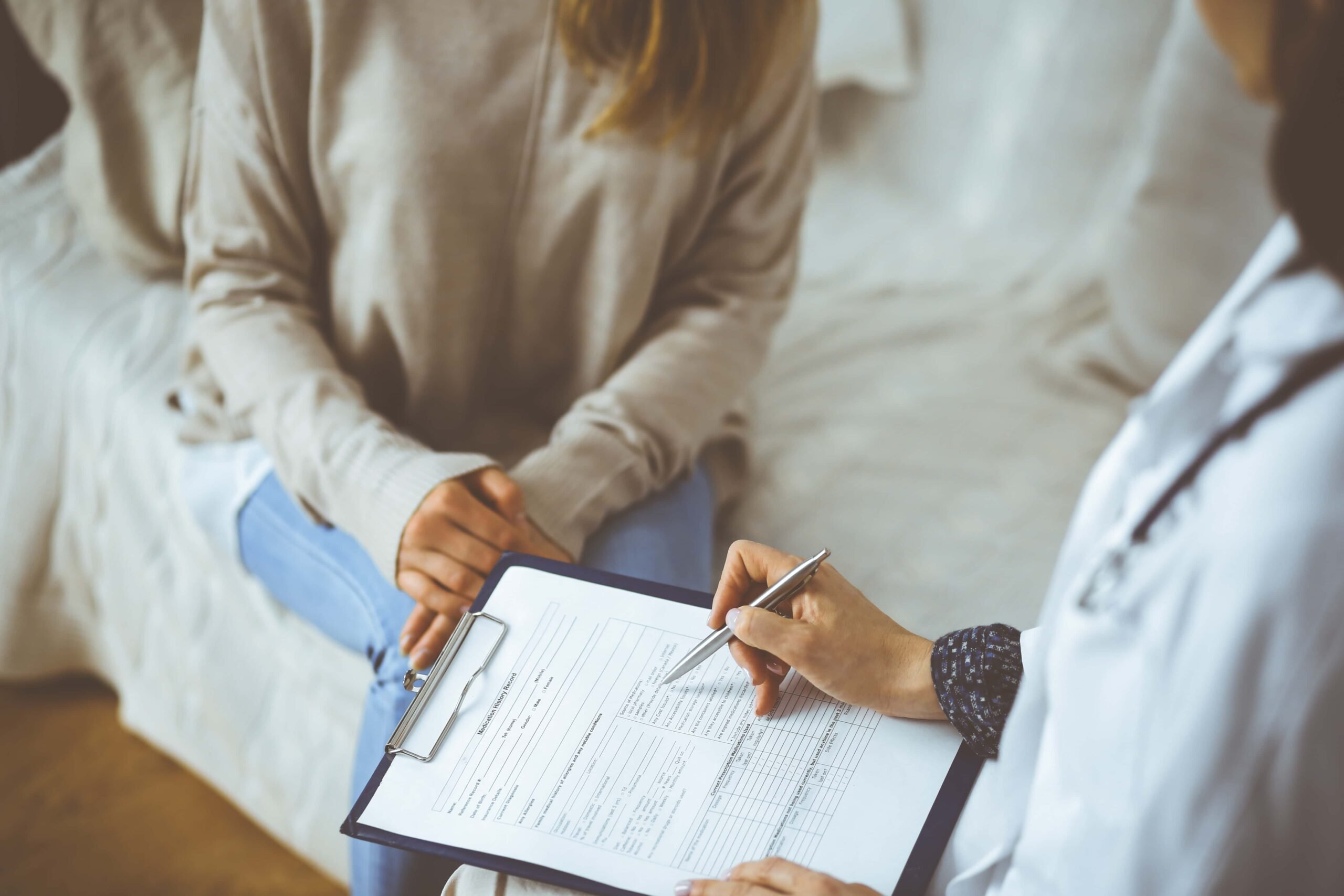 cropped shot of doctor writing down perscription for female patient scaled